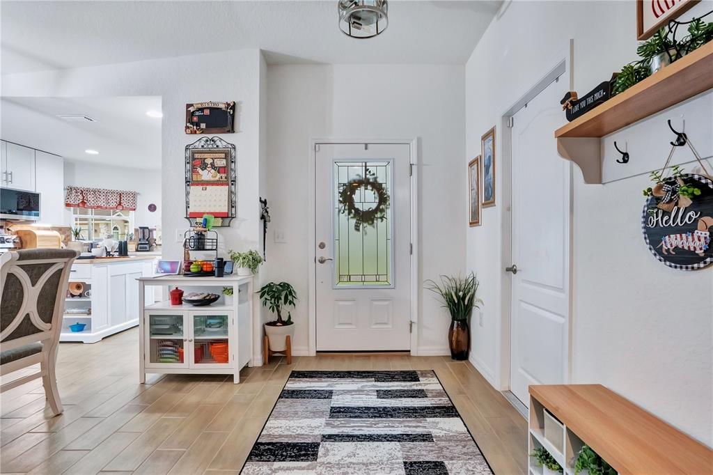 An entryway features a white front door, light wood-look flooring, and a patterned area rug — 1153 BISHOP STREET, AVON PARK, FL