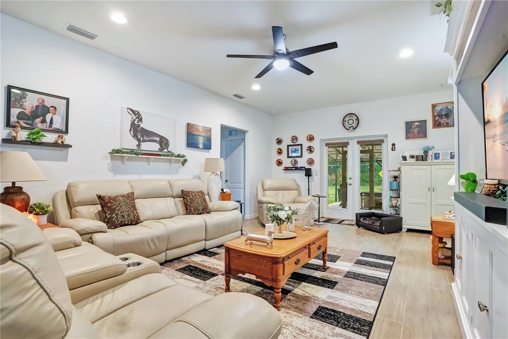 A living room features light-colored leather sofas, a wooden coffee table, and a ceiling fan — 1153 BISHOP STREET, AVON PARK, FL