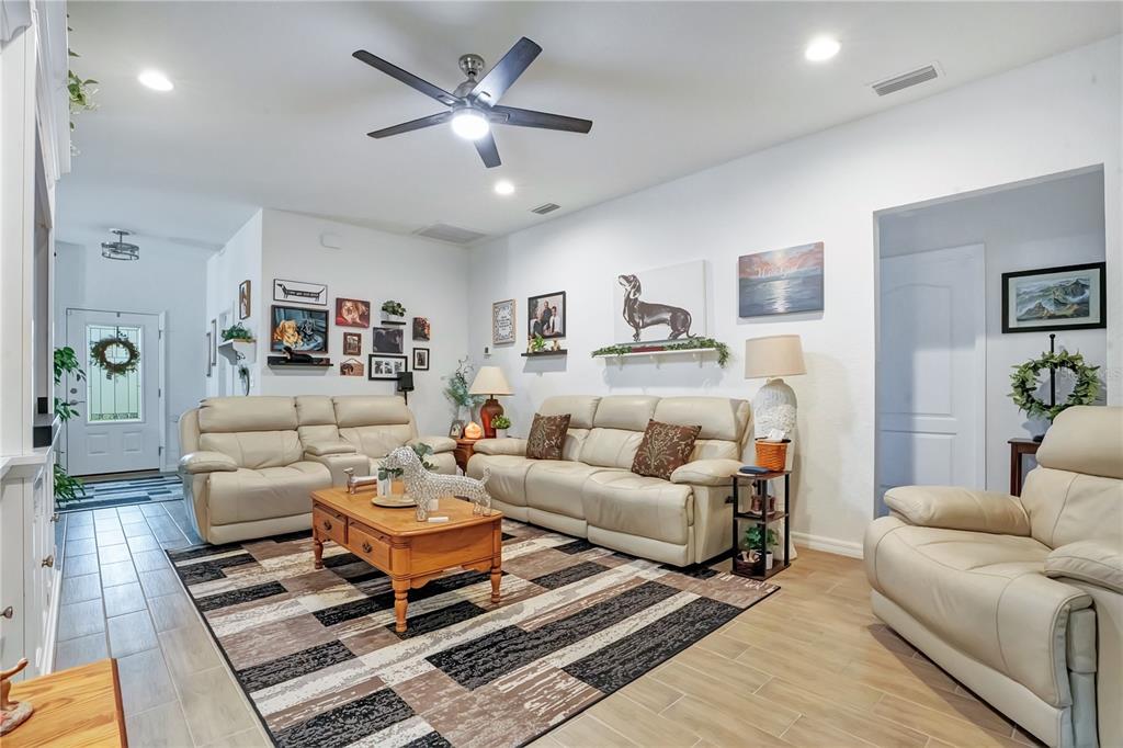 A living room features light-colored leather sofas, a wooden coffee table, and a geometric rug — 1153 BISHOP STREET, AVON PARK, FL