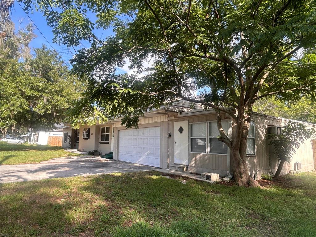 A single-story house with a white garage door, tan siding, and a large shade tree — 2009 POE STREET, LAKELAND, FL