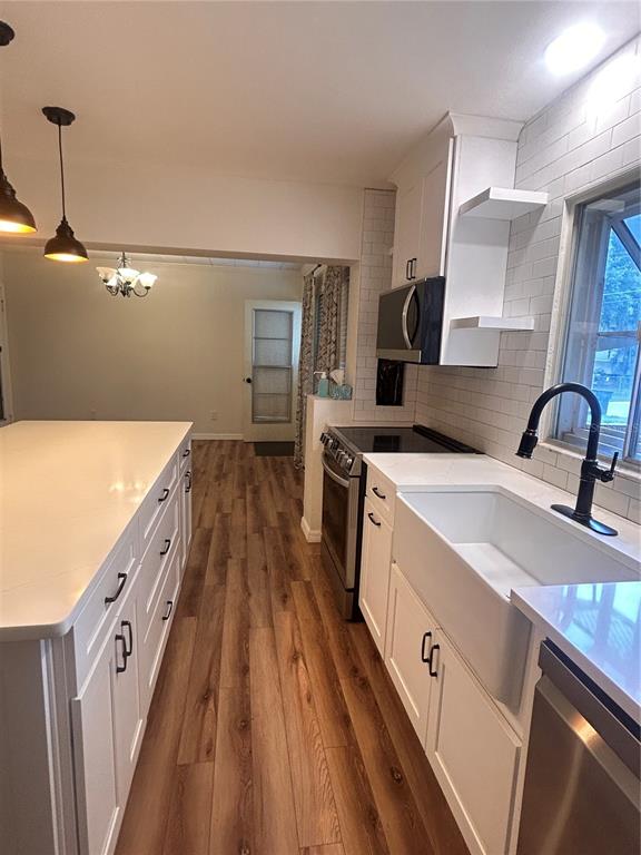 A kitchen features white cabinets, a farmhouse sink, a kitchen island, and wood-look flooring — 2009 POE STREET, LAKELAND, FL