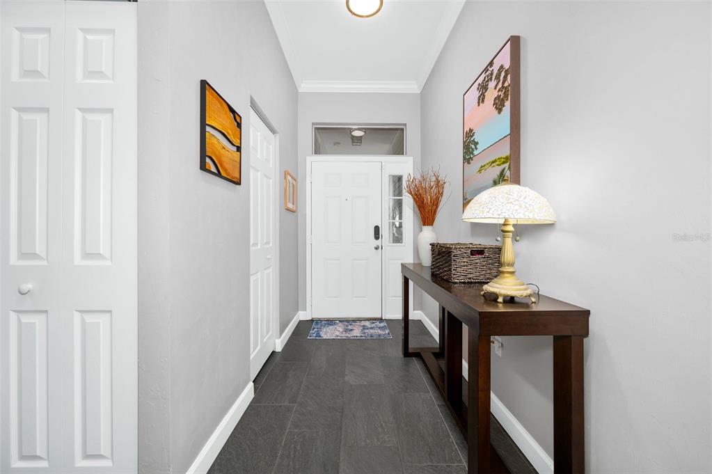 A bright entryway features dark tile flooring, a console table with a lamp, and white doors — 9044 SW 25TH ROAD, GAINESVILLE, FL