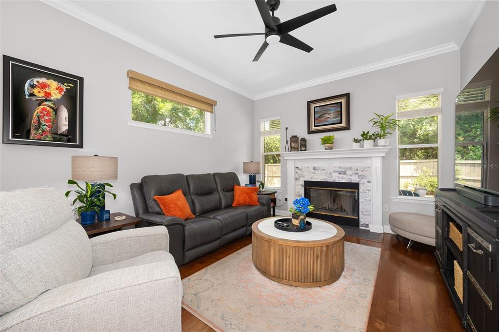A living room features a fireplace, a dark leather sofa, and a light-colored armchair — 9044 SW 25TH ROAD, GAINESVILLE, FL