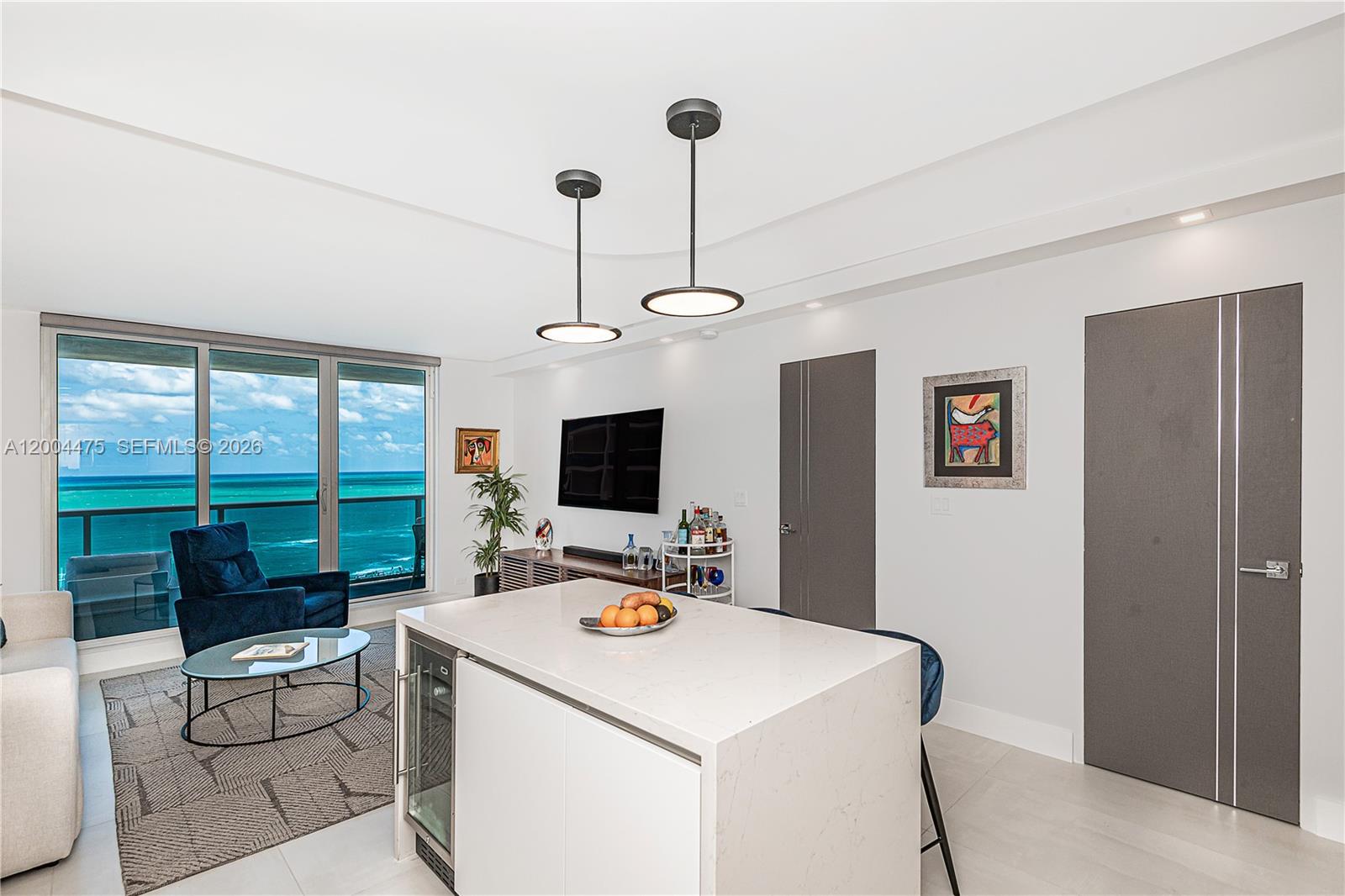 A modern kitchen island with a wine cooler faces a living area with ocean views — 2301 Collins Ave # 1440, Miami Beach FL 33139, MIAMI BEACH, FL