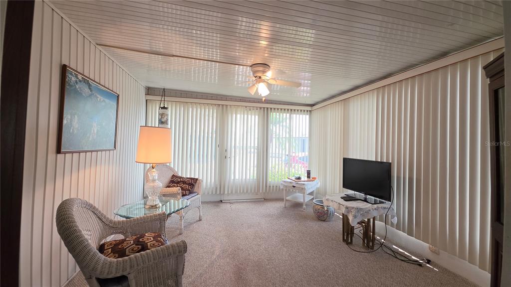 A sunroom features vertical blinds, a ceiling fan, carpeted flooring, and wicker furniture — 5406 BALI COURT, BRADENTON, FL