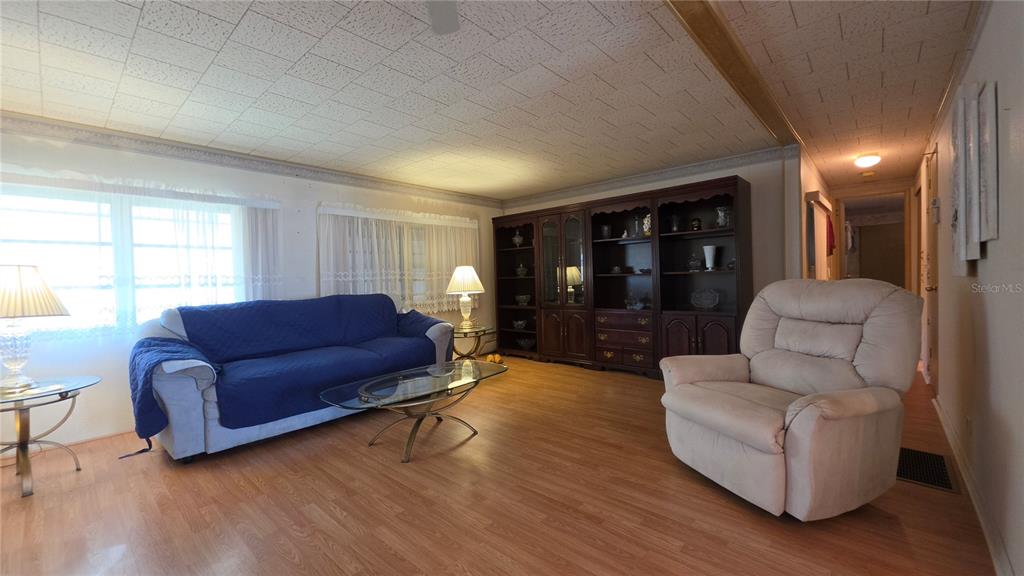 A living room features wood-look flooring, a blue sofa, a recliner, and a large wall unit — 5406 BALI COURT, BRADENTON, FL