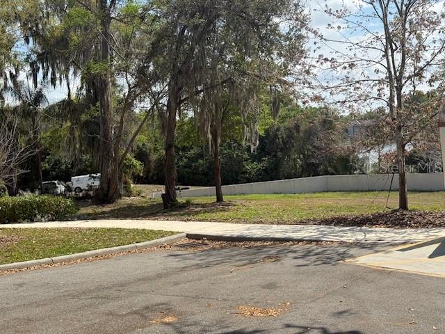 A paved parking area sits in front of a grassy lot with trees and a fence — 610 JASMINE ROAD, ALTAMONTE SPRINGS, FL