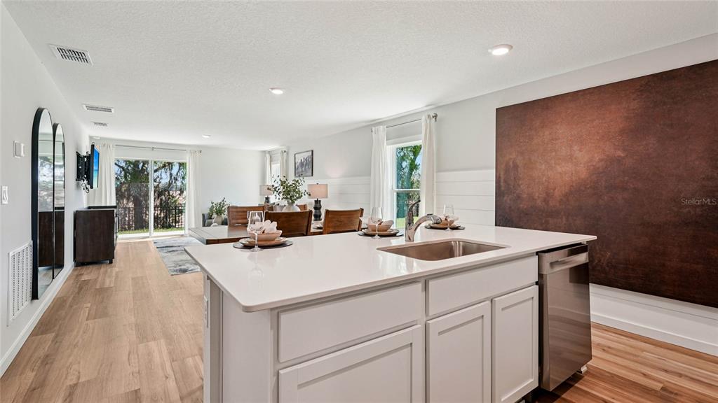 A kitchen island with a sink and dishwasher overlooks an open dining and living area — 3067 HOUSE FINCH ROAD, ST CLOUD, FL