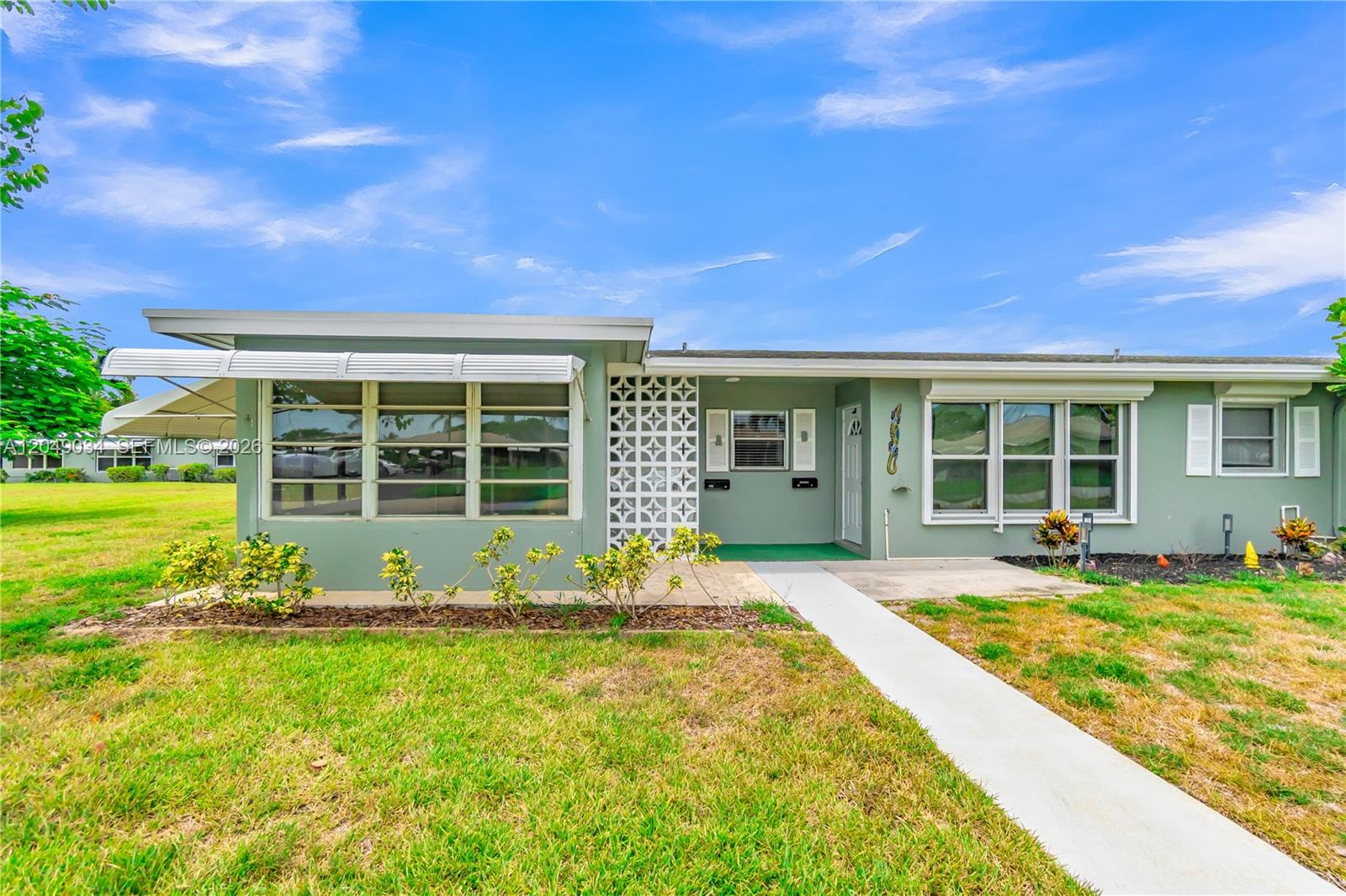 A single-story green house with a decorative breeze block screen and a concrete walkway — 775 North Dr # A, Delray Beach FL 33445, DELRAY BEACH, FL