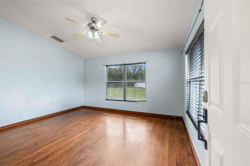 An empty room with light blue walls, wood-look flooring, a ceiling fan, and a window — 6114 SCHOOL HOUSE COURT, WESLEY CHAPEL, FL