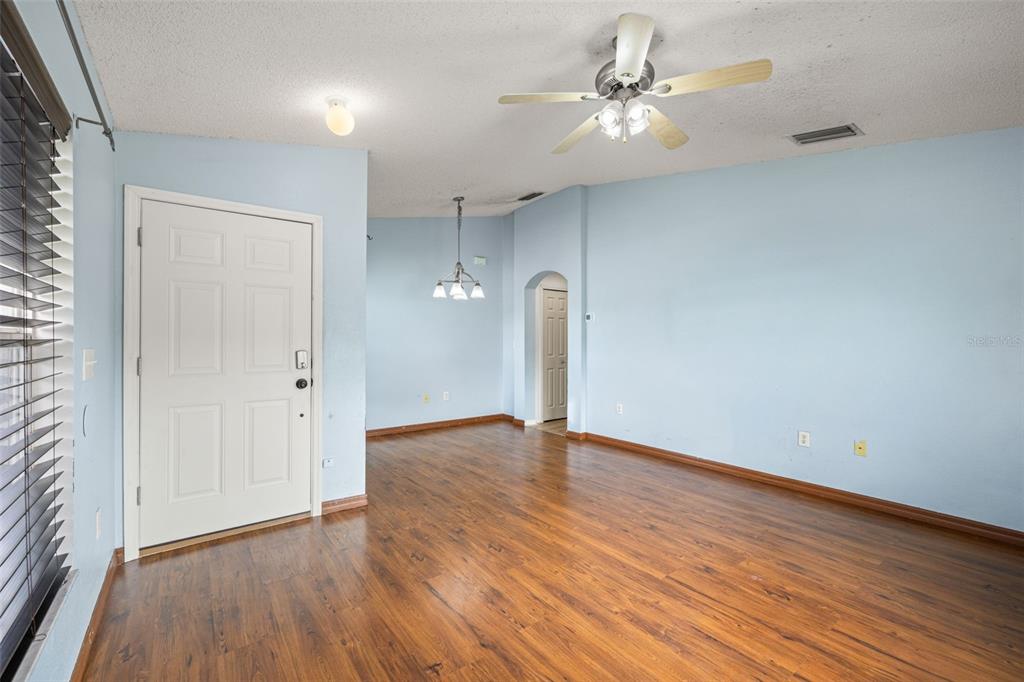 An empty room with light blue walls, wood-look flooring, a ceiling fan, and a door — 6114 SCHOOL HOUSE COURT, WESLEY CHAPEL, FL