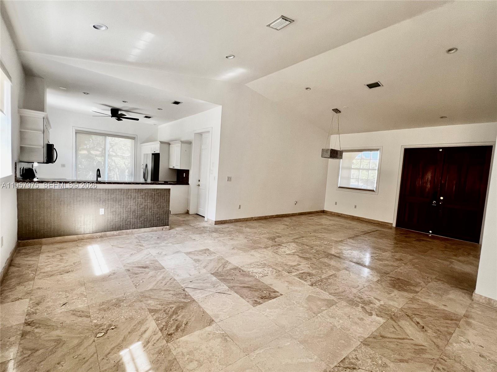 An open-concept living area features a kitchen with a breakfast bar and stone tile flooring — 2301 SW 22nd Ave, Miami FL 33145, MIAMI, FL