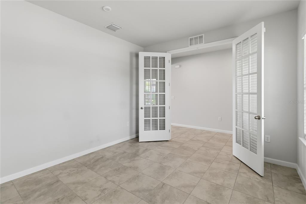 A room with light gray walls, tile flooring, and white French doors leading to another space — 5581 VIGO LOOP, ST CLOUD, FL