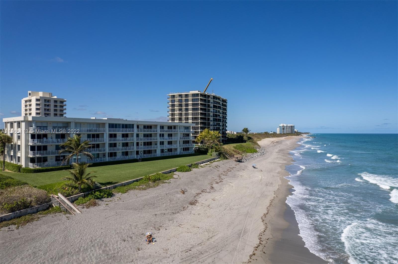 An aerial view shows a multi-story apartment building situated next to a sandy beach — 350 S Beach Road # 205, Jupiter FL 33469, JUPITER, FL