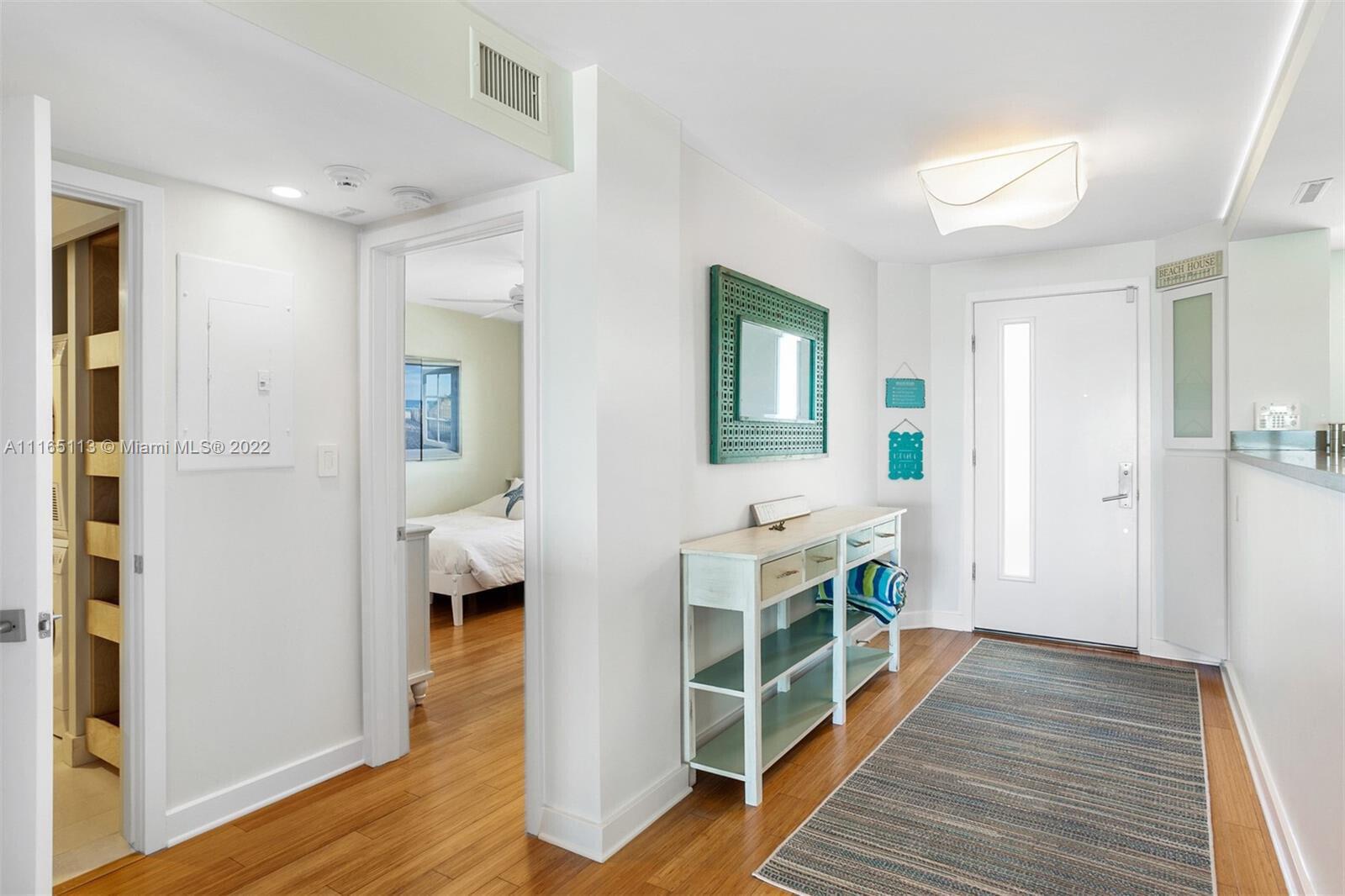 An entryway features hardwood floors, a console table, a mirror, and a view into a bedroom — 350 S Beach Road # 205, Jupiter FL 33469, JUPITER, FL
