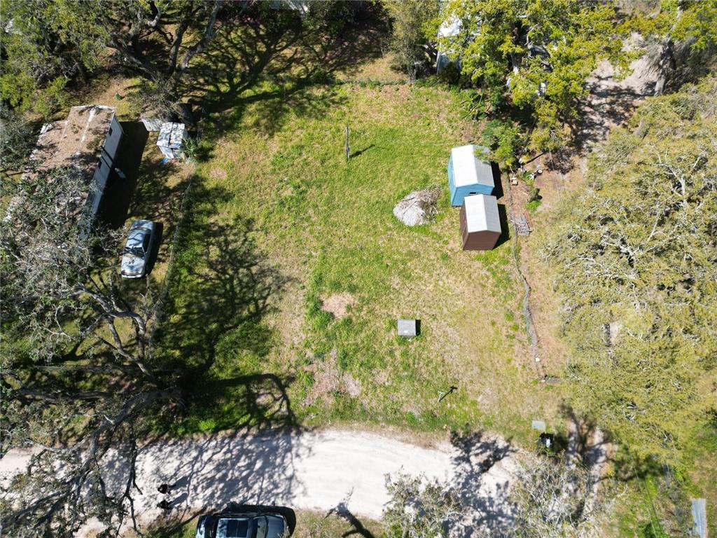 An aerial view shows a grassy lot with two small sheds and a parked car — 4919 HURON STREET, ZEPHYRHILLS, FL