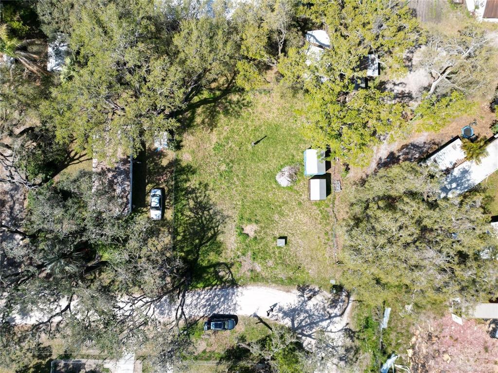 An aerial view shows a grassy lot with several trees, two small sheds, and a vehicle — 4919 HURON STREET, ZEPHYRHILLS, FL