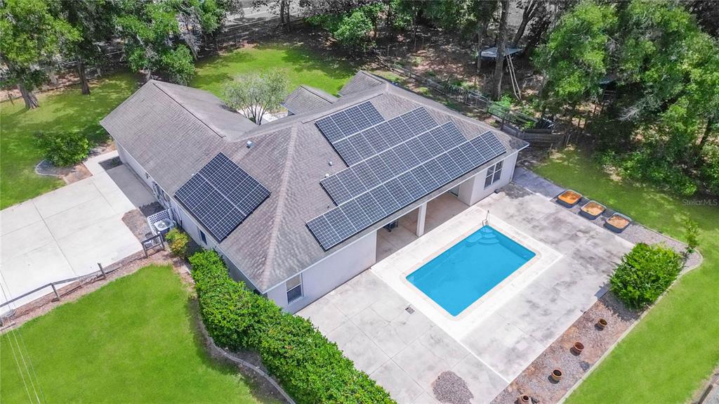 An aerial view of a house with solar panels, a swimming pool, and a large yard — 150 NE 49TH STREET, OCALA, FL
