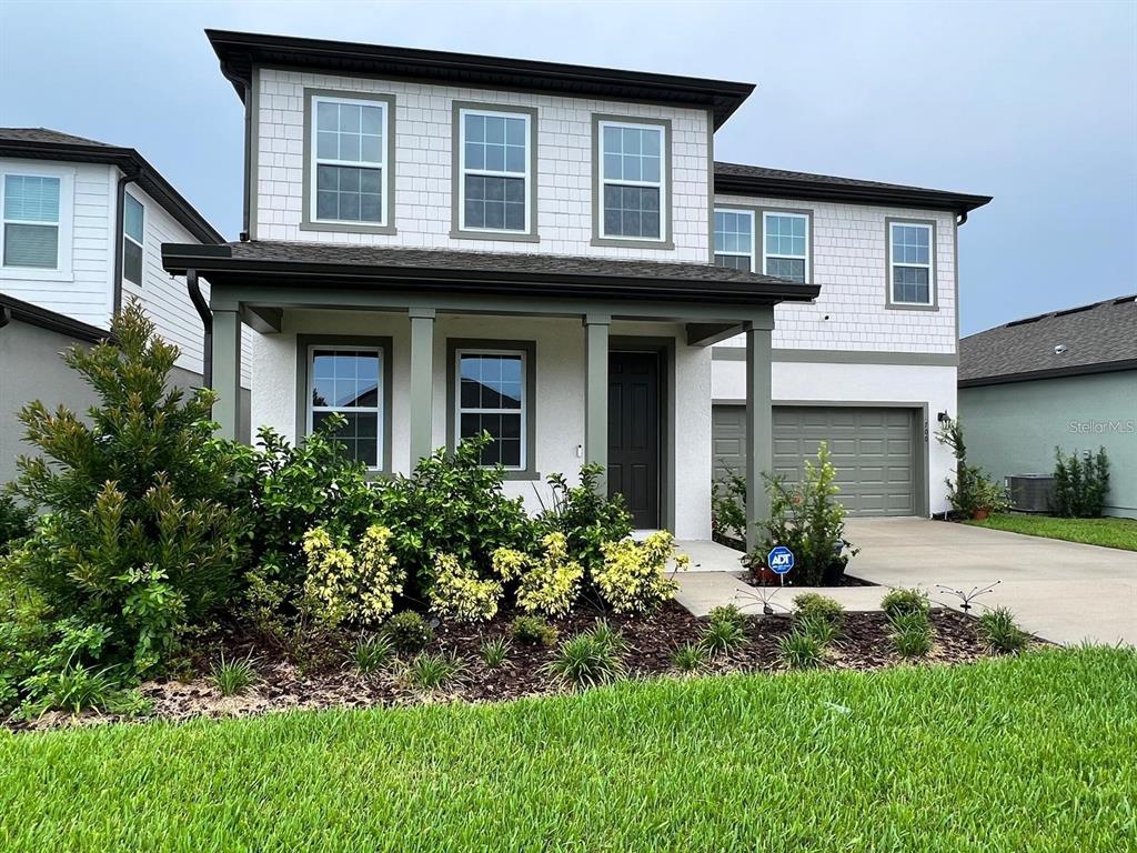 A two-story suburban house features a white exterior, dark trim, and a front-facing garage — 700 SPLIT HOOF DRIVE, ST CLOUD, FL