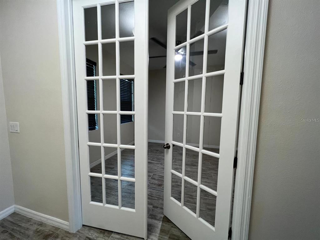 White French doors open into a room with wood-look tile flooring and a ceiling fan — 700 SPLIT HOOF DRIVE, ST CLOUD, FL