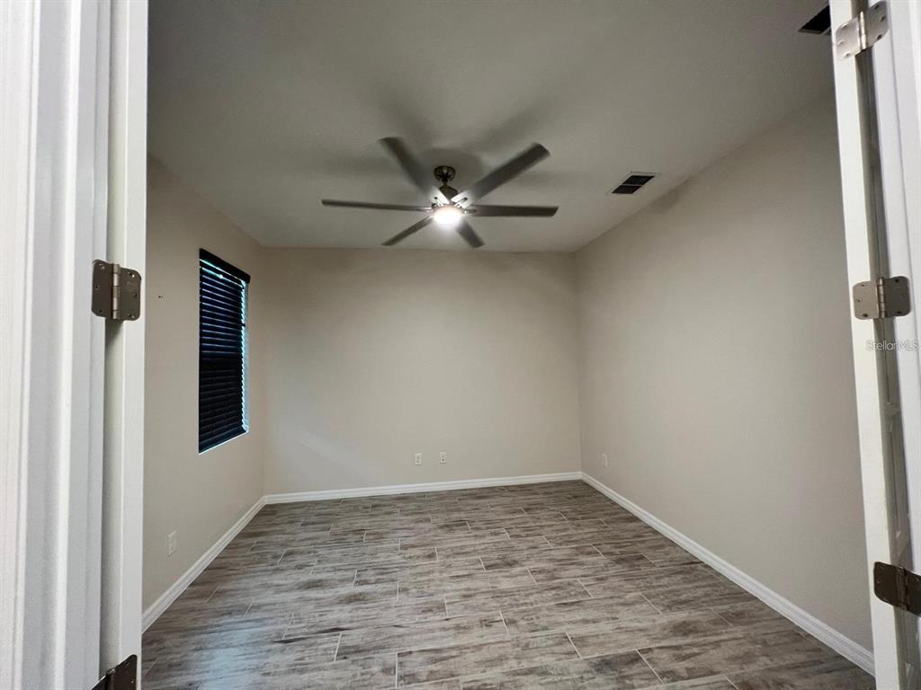 An empty room with light-colored walls, a ceiling fan, and wood-look tile flooring — 700 SPLIT HOOF DRIVE, ST CLOUD, FL