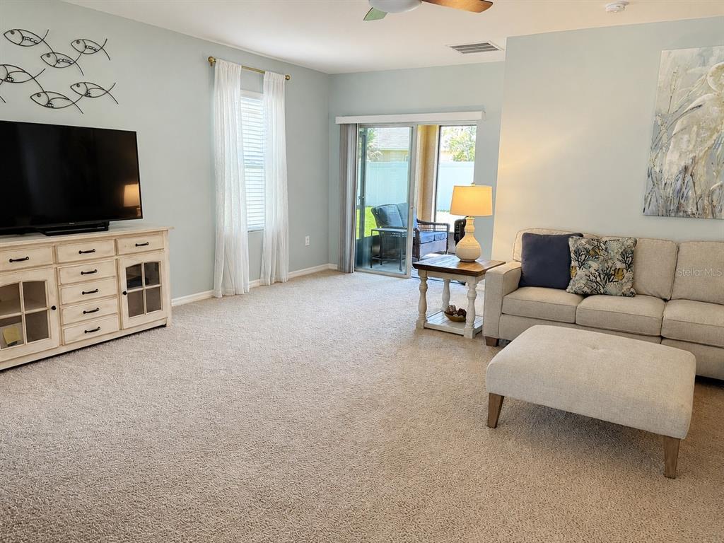 A living room features a television console, a beige sofa with an ottoman, and sliding doors — 2719 STAR CORAL LANE, NEW SMYRNA BEACH, FL