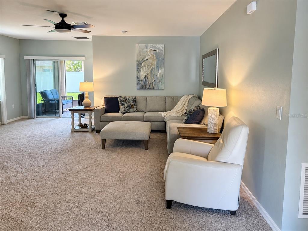 A living room features a sectional sofa, an ottoman, a recliner, and a sliding glass door — 2719 STAR CORAL LANE, NEW SMYRNA BEACH, FL