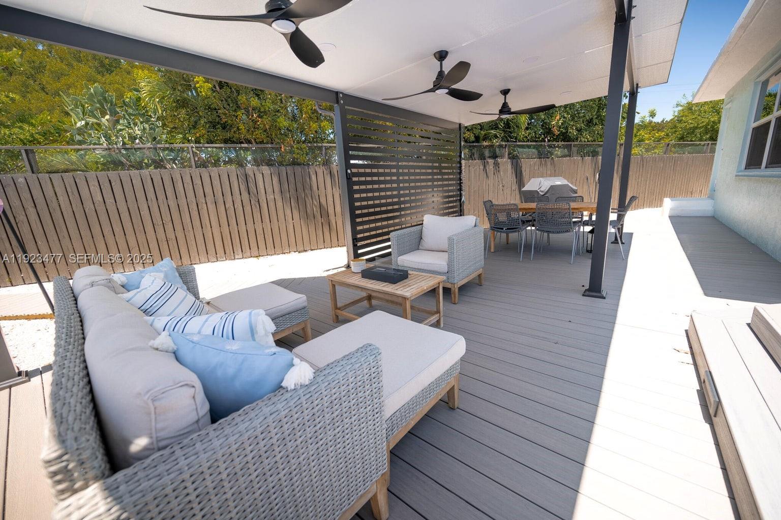 A covered outdoor patio features gray composite decking, wicker furniture, and a slatted privacy screen — 212 Buttonwood Ln, Key Largo FL 33070, KEY LARGO, FL