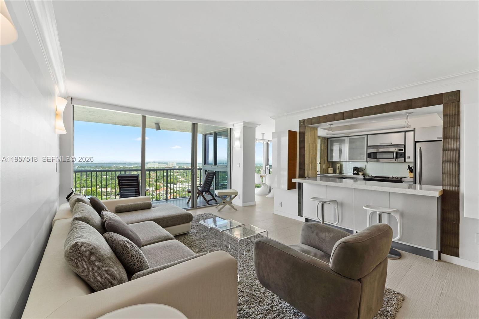 A modern living room with a sectional sofa, kitchen bar, and floor-to-ceiling balcony windows — 2655 Collins Ave # 2301, Miami Beach FL 33140, MIAMI BEACH, FL