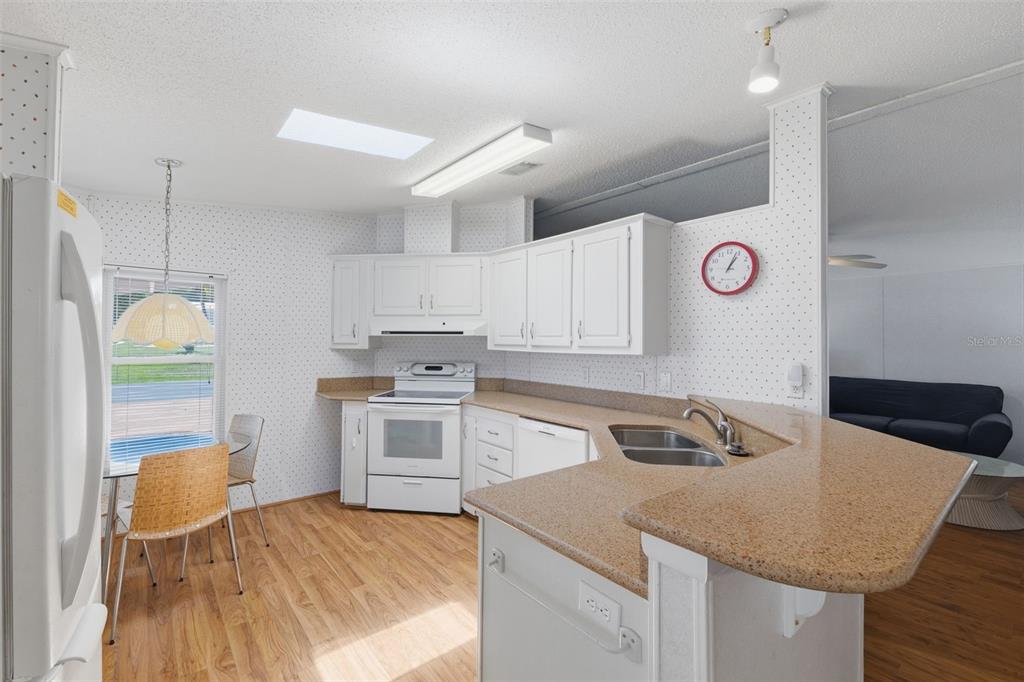 A kitchen with white cabinets, speckled countertops, wood-look flooring, and a dining area — 520 TIVOLI PARK DRIVE, DAVENPORT, FL