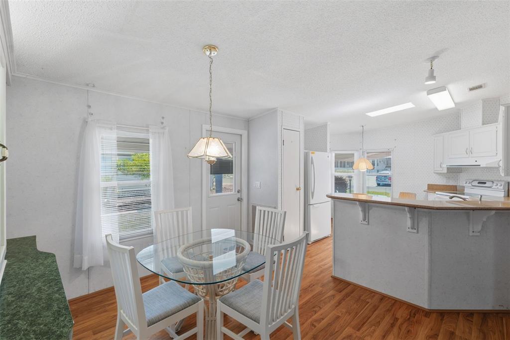 A dining area with a glass table and chairs sits adjacent to an open kitchen — 520 TIVOLI PARK DRIVE, DAVENPORT, FL