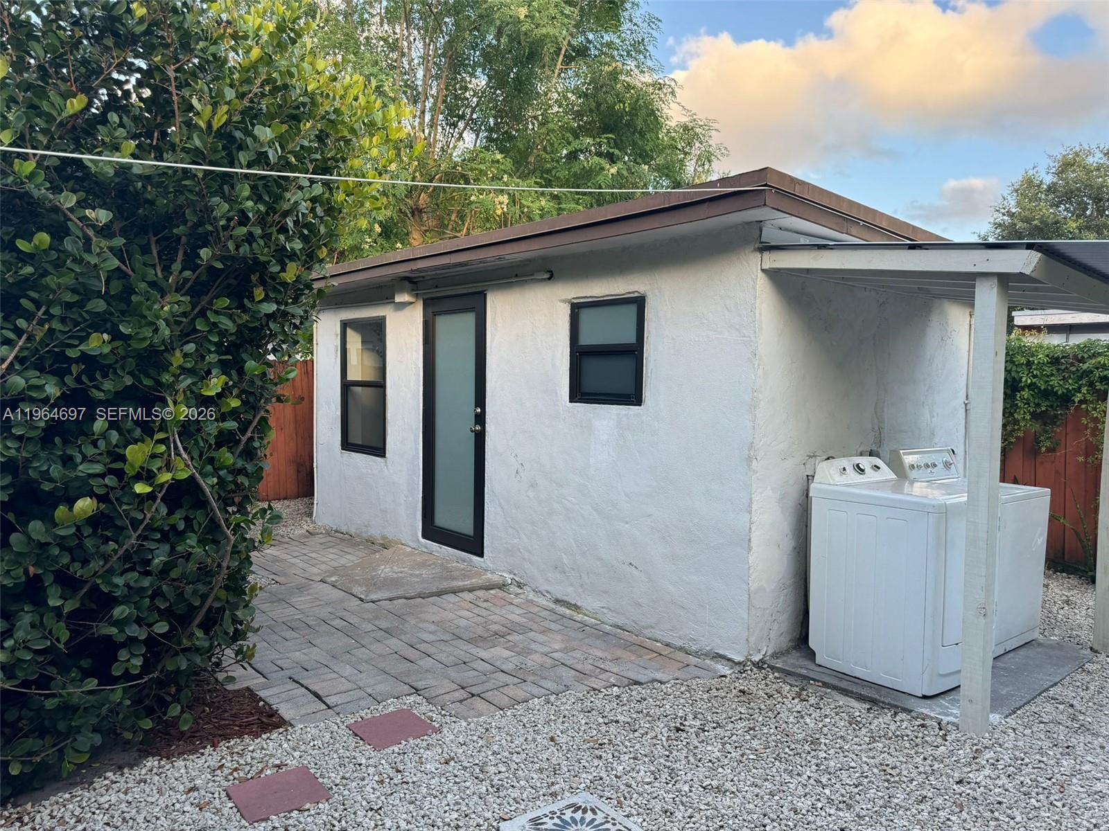 A small white detached structure features a glass door, two windows, and an outdoor laundry area — 1756 NW 94th St, Miami FL 33147, MIAMI, FL