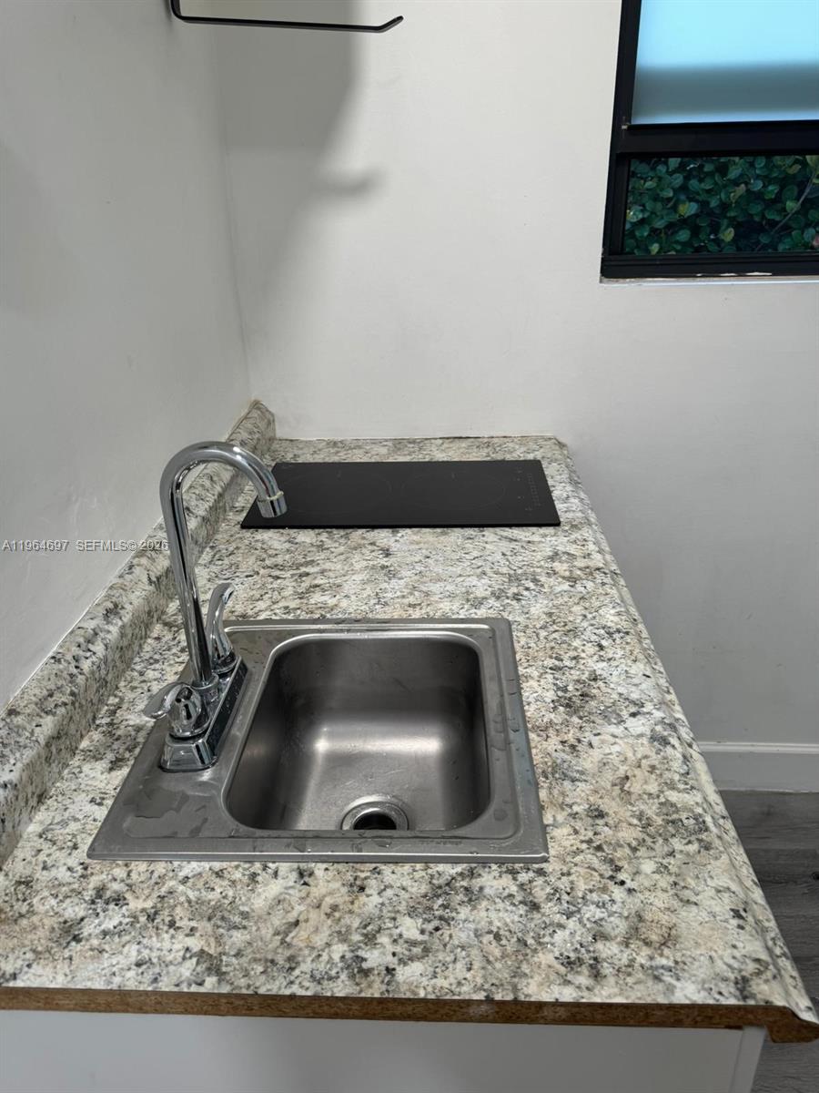 A small kitchen area features a stainless steel sink and a black electric cooktop — 1756 NW 94th St, Miami FL 33147, MIAMI, FL