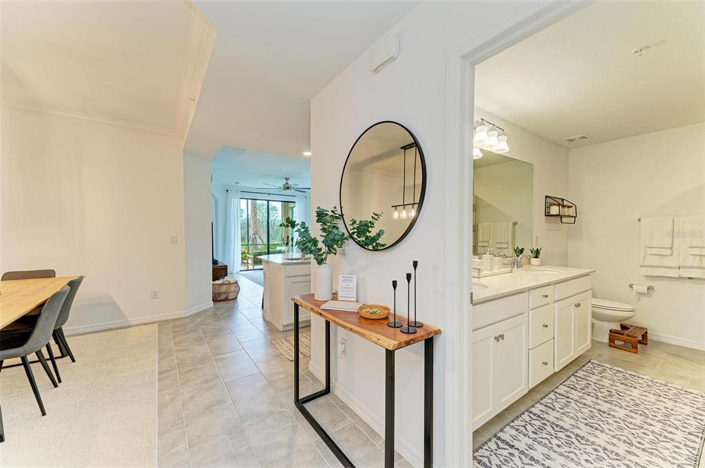 A hallway connects a dining area to a bathroom and an open-concept kitchen beyond — 18114 GAWTHROP DRIVE UNIT 108, BRADENTON, FL