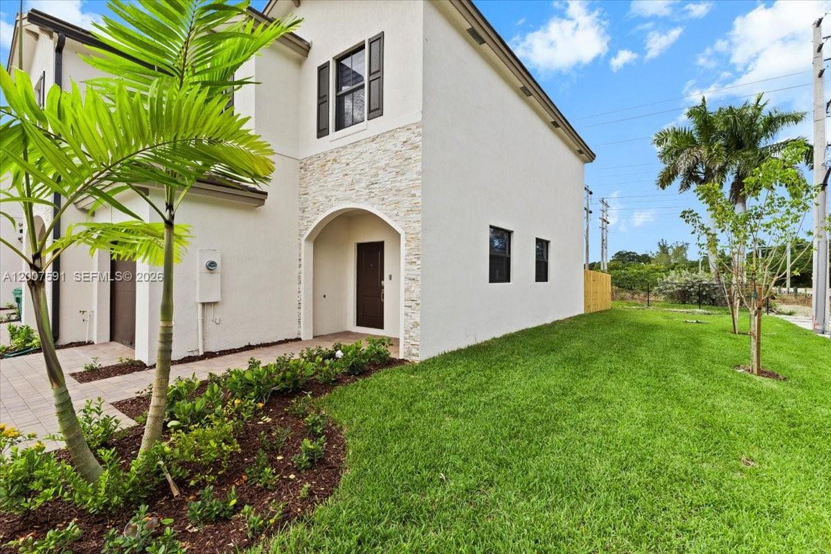 The exterior of a two-story house features a stone-accented entryway and a grassy side yard — 23210 SW 133rd Ct, Miami FL 33032, MIAMI, FL