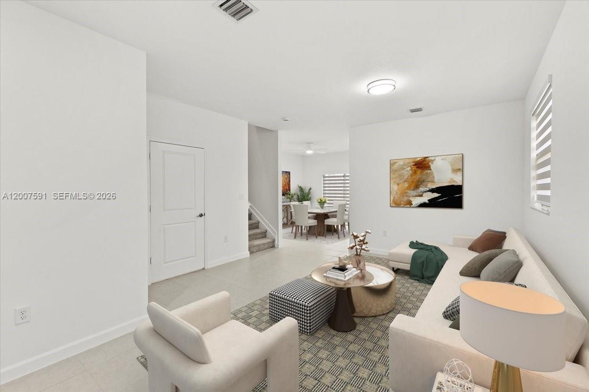 This living room features white walls, tile flooring, a beige sofa, and a dining area — 23210 SW 133rd Ct, Miami FL 33032, MIAMI, FL