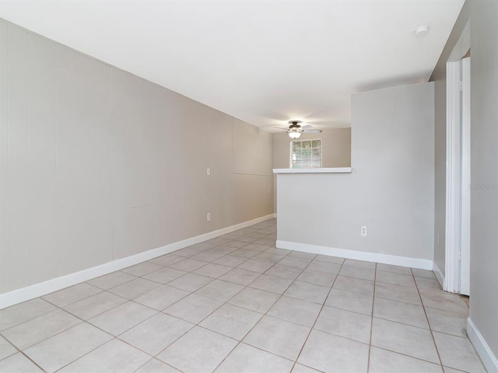 An empty room with light gray walls, tiled flooring, and a partial wall divider — 104 KARDE LANE UNIT A, BRANDON, FL