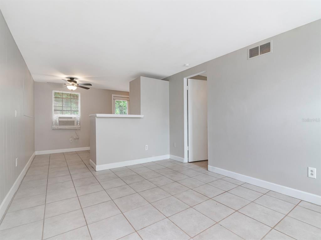 A living area with light gray walls, tile flooring, a ceiling fan, and a half wall — 104 KARDE LANE UNIT A, BRANDON, FL