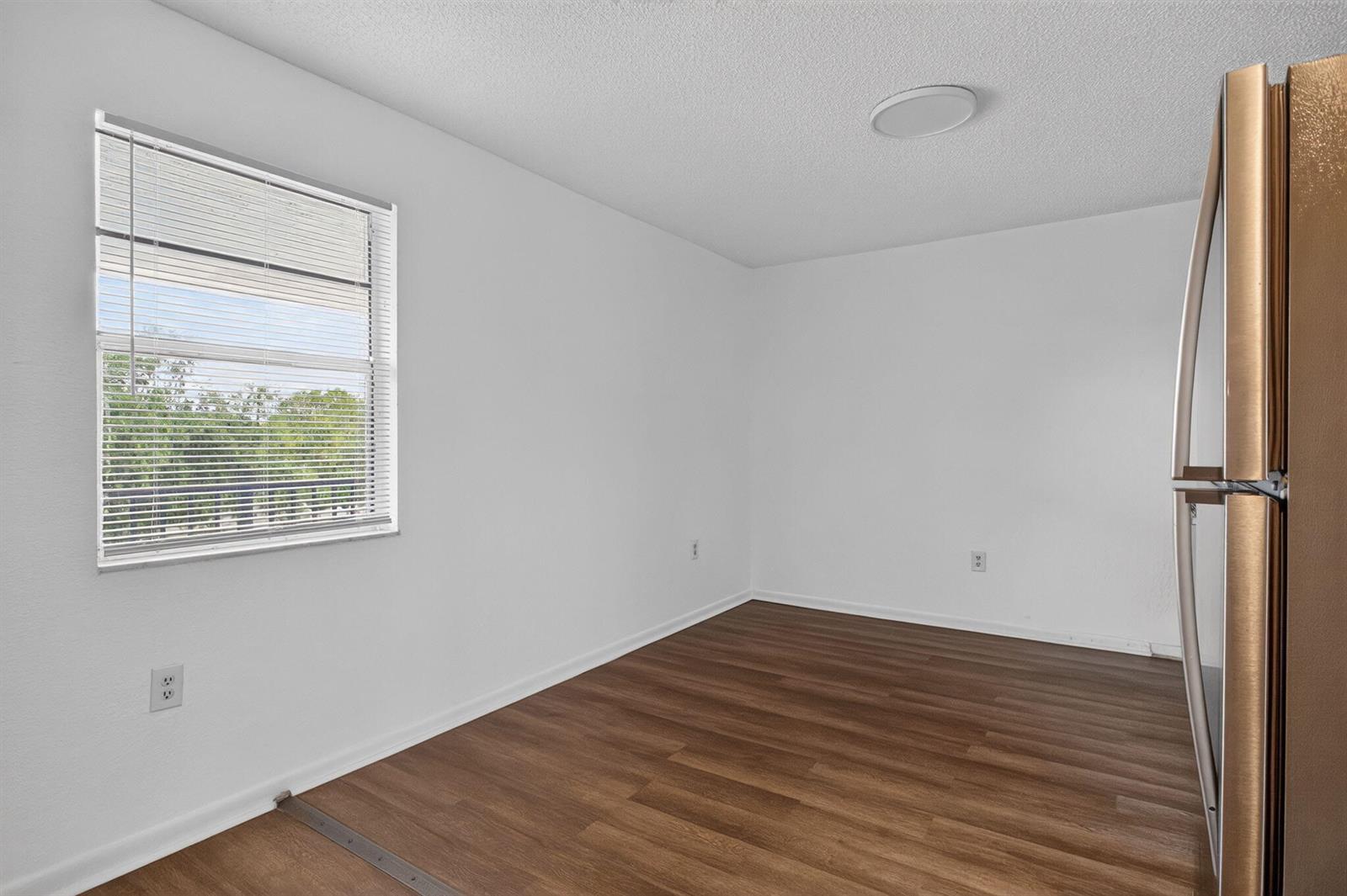 An empty room with white walls, wood-look flooring, a window with blinds, and a refrigerator — 1300 NW 2nd Avenue # 12, Pompano Beach FL 33060, POMPANO BEACH, FL