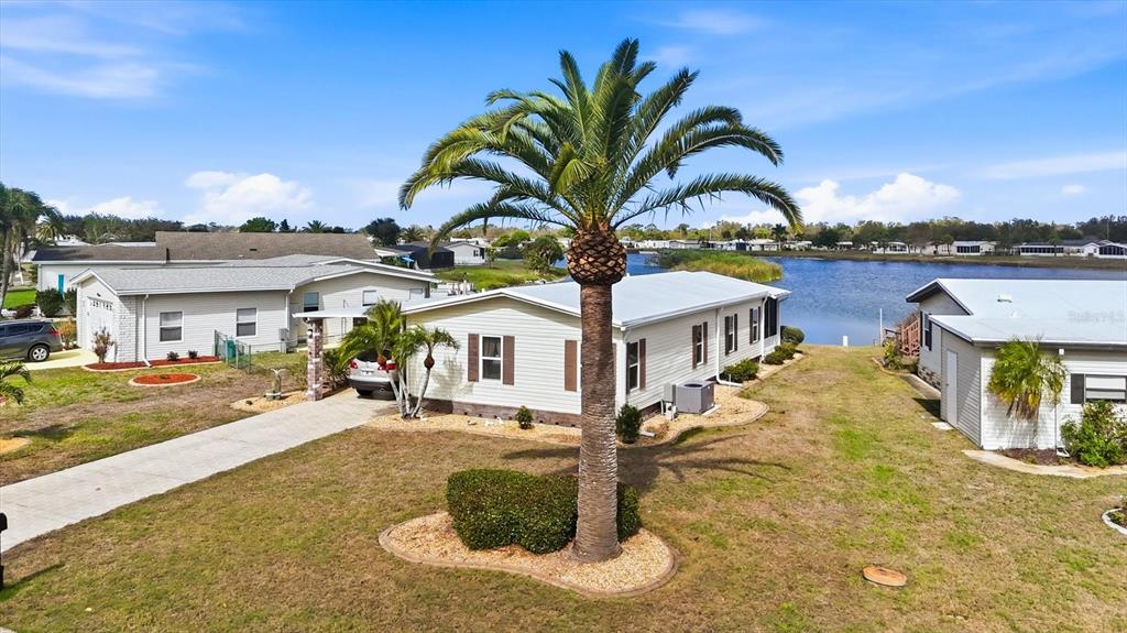 An aerial view of a light-colored manufactured home with a palm tree in the yard — 6085 SHEARWATER DRIVE, ENGLEWOOD, FL