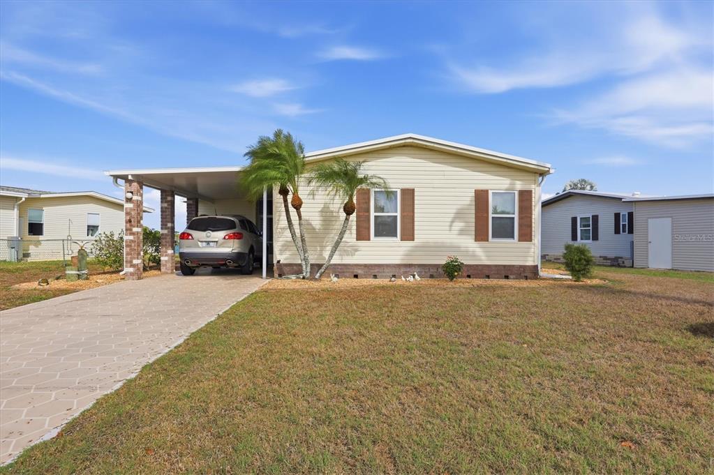 A single-story house with light siding, a carport, and a paved driveway — 6085 SHEARWATER DRIVE, ENGLEWOOD, FL
