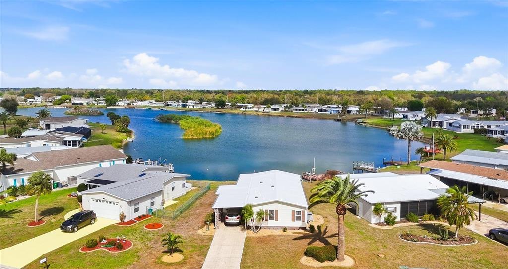 An aerial view shows several single-story homes situated along the edge of a lake — 6085 SHEARWATER DRIVE, ENGLEWOOD, FL