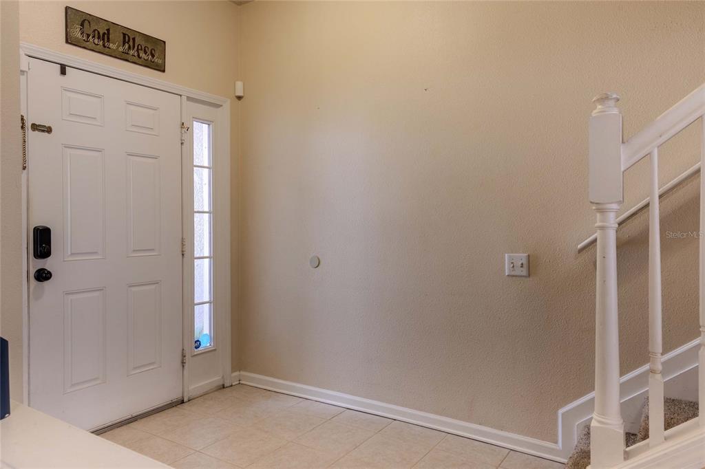 An entryway features a white front door, tiled flooring, and a staircase with white railings — 2720 CONCH HOLLOW DRIVE, BRANDON, FL