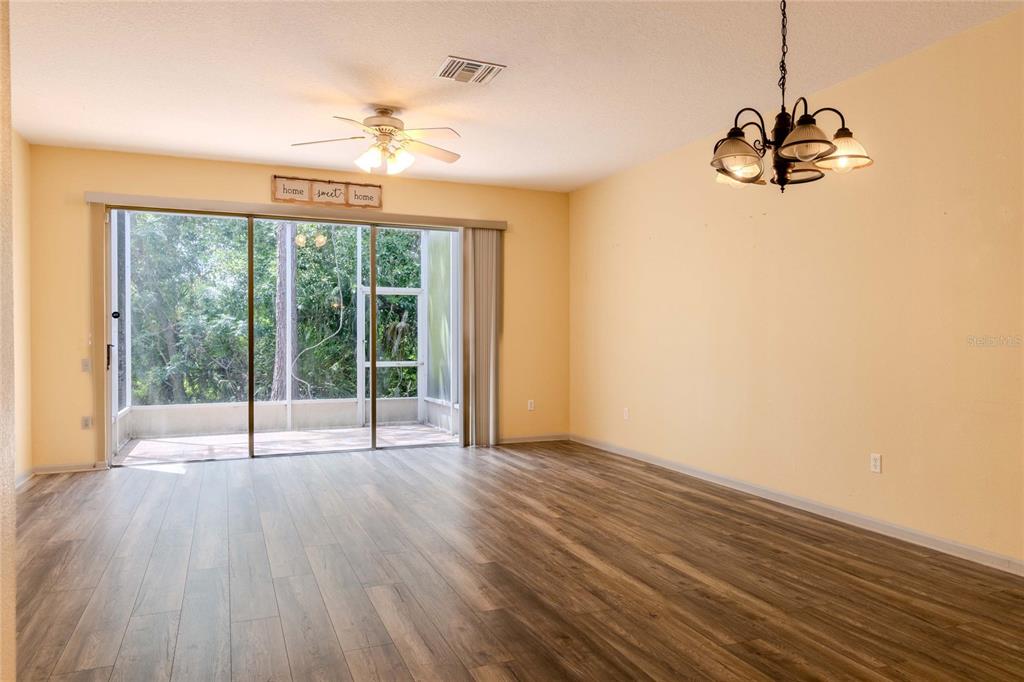 An empty room with light yellow walls, wood-look flooring, a ceiling fan, and sliding doors — 2720 CONCH HOLLOW DRIVE, BRANDON, FL