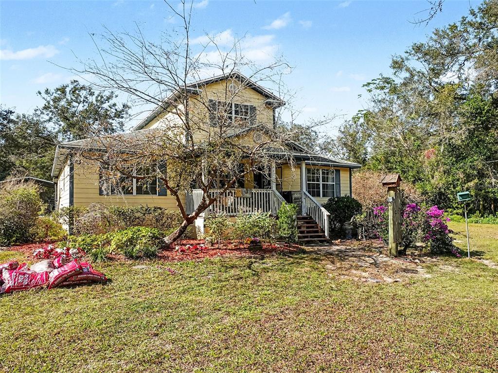 A two-story yellow house with a front porch stands on a grassy lot — 4400 CONRAD ACRES LANE, APOPKA, FL