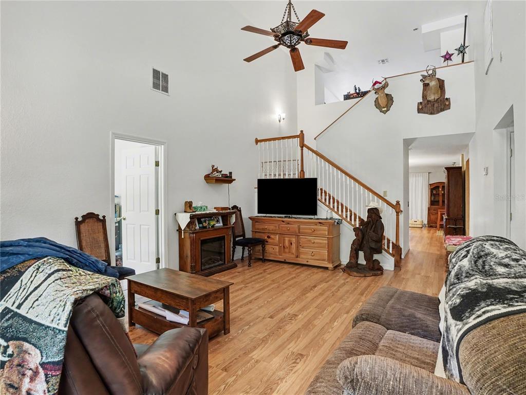 A living room with high ceilings, wood flooring, a staircase, and a television on a dresser — 4400 CONRAD ACRES LANE, APOPKA, FL