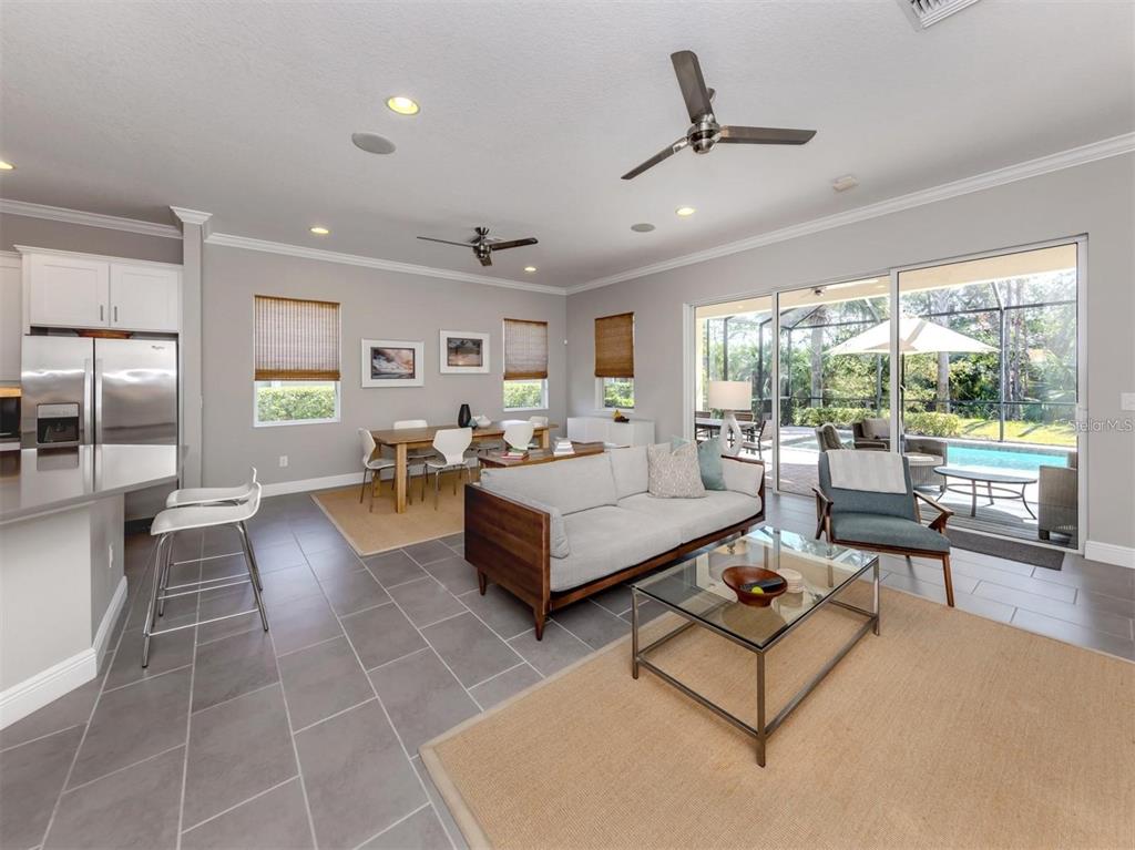 An open-concept living and dining area features tile flooring, a kitchen island, and sliding glass doors — 500 PADOVA WAY, NORTH VENICE, FL