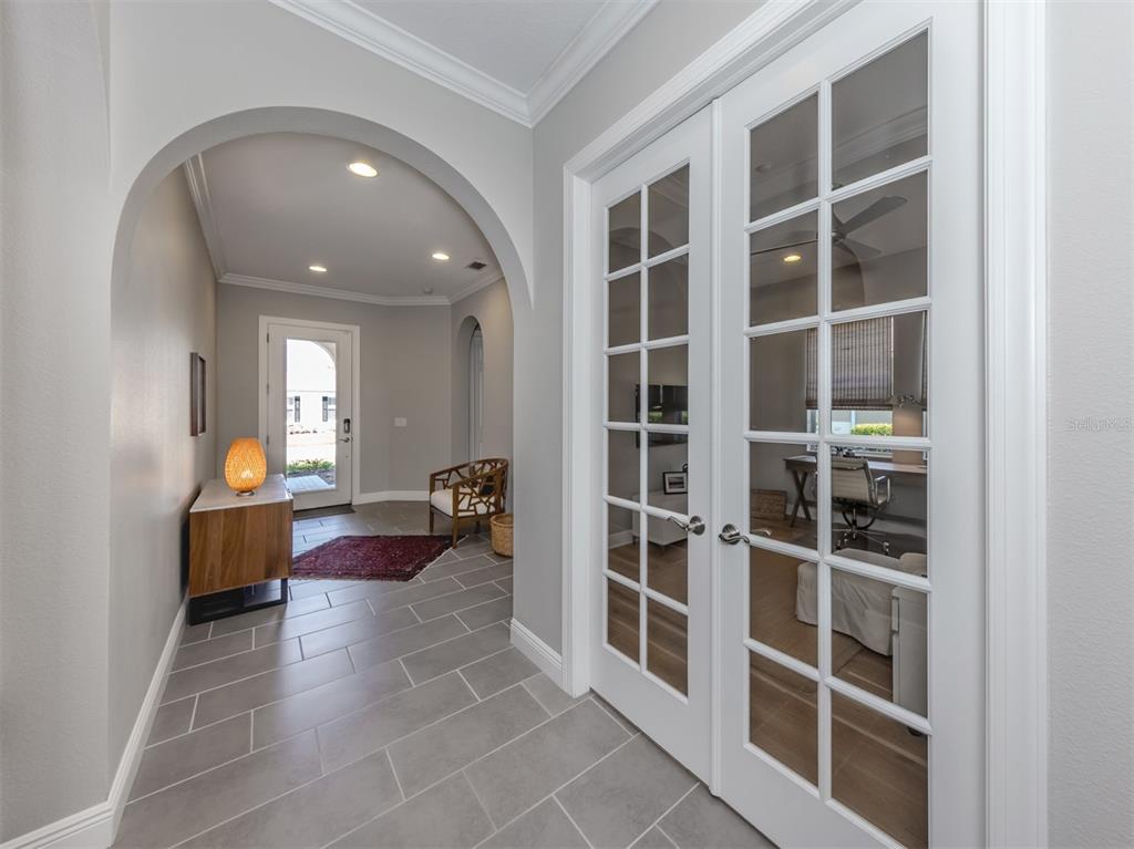 A tiled entryway features an arched opening, a wooden console table, and white French doors — 500 PADOVA WAY, NORTH VENICE, FL