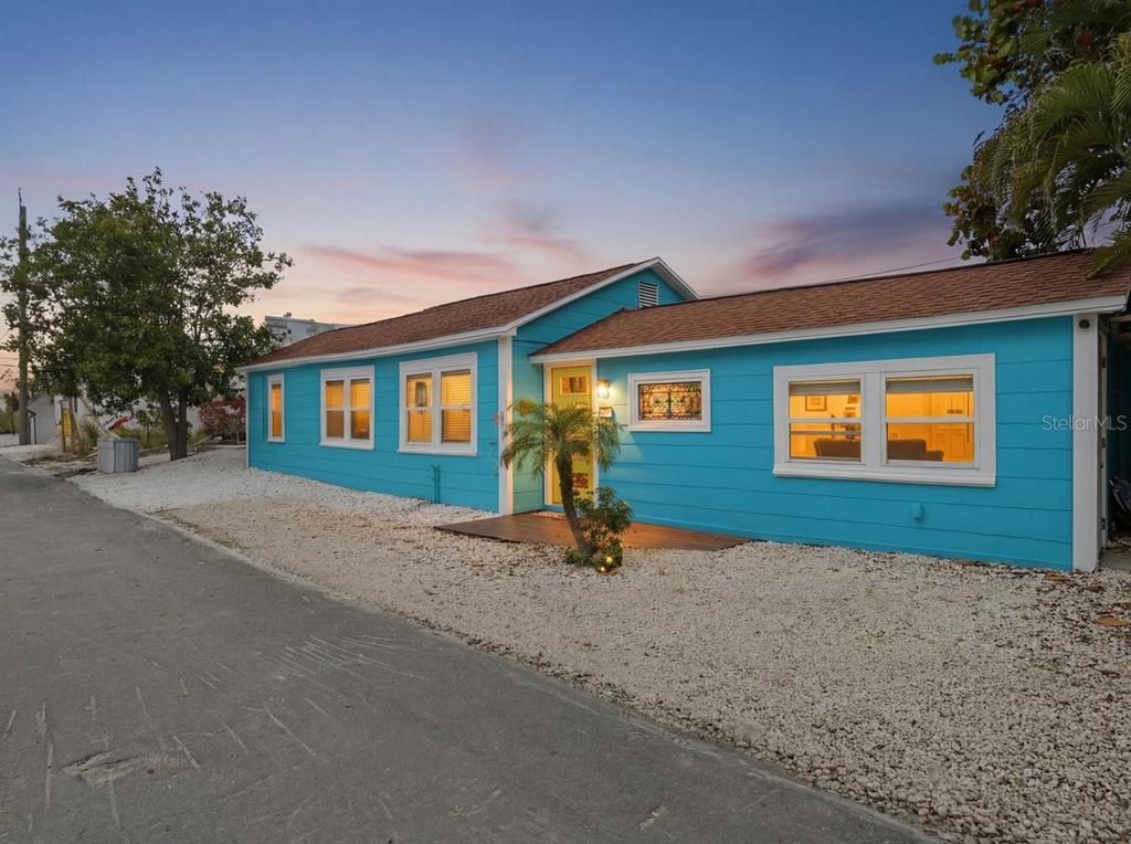 A bright blue single-story house with a brown roof sits beside a paved road — 118 92ND AVENUE, TREASURE ISLAND, FL