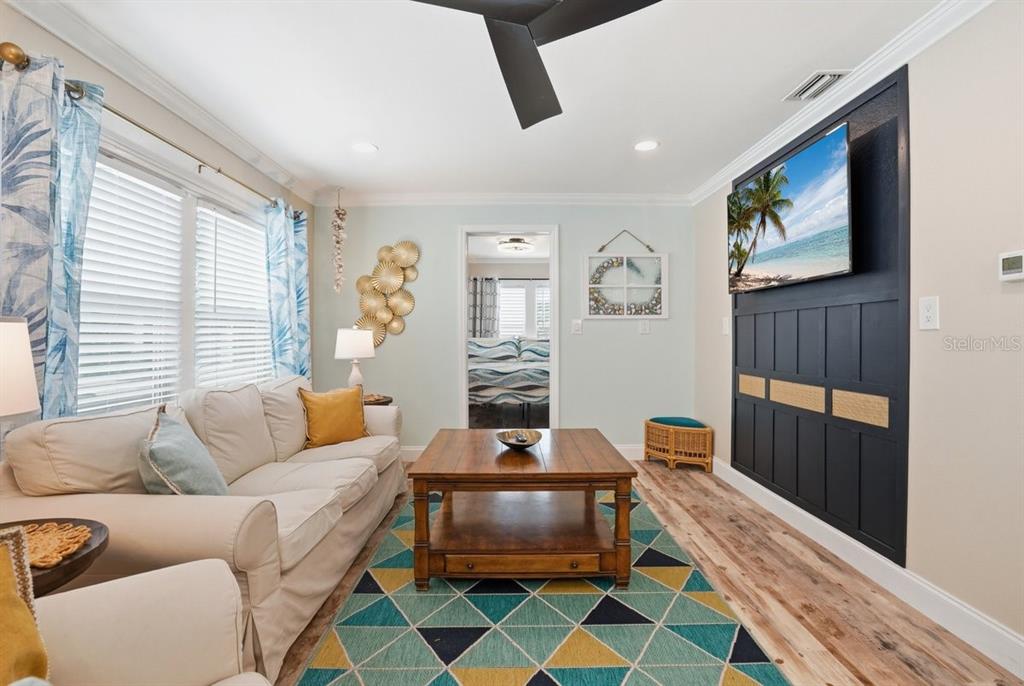 A living room features a white sofa, a wooden coffee table, and a dark accent wall — 118 92ND AVENUE, TREASURE ISLAND, FL